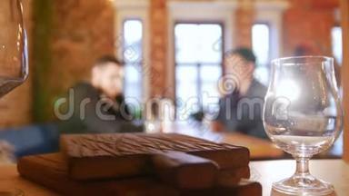 两个人坐在餐馆的一张桌子旁，给服务员打电话。 对焦的眼镜
